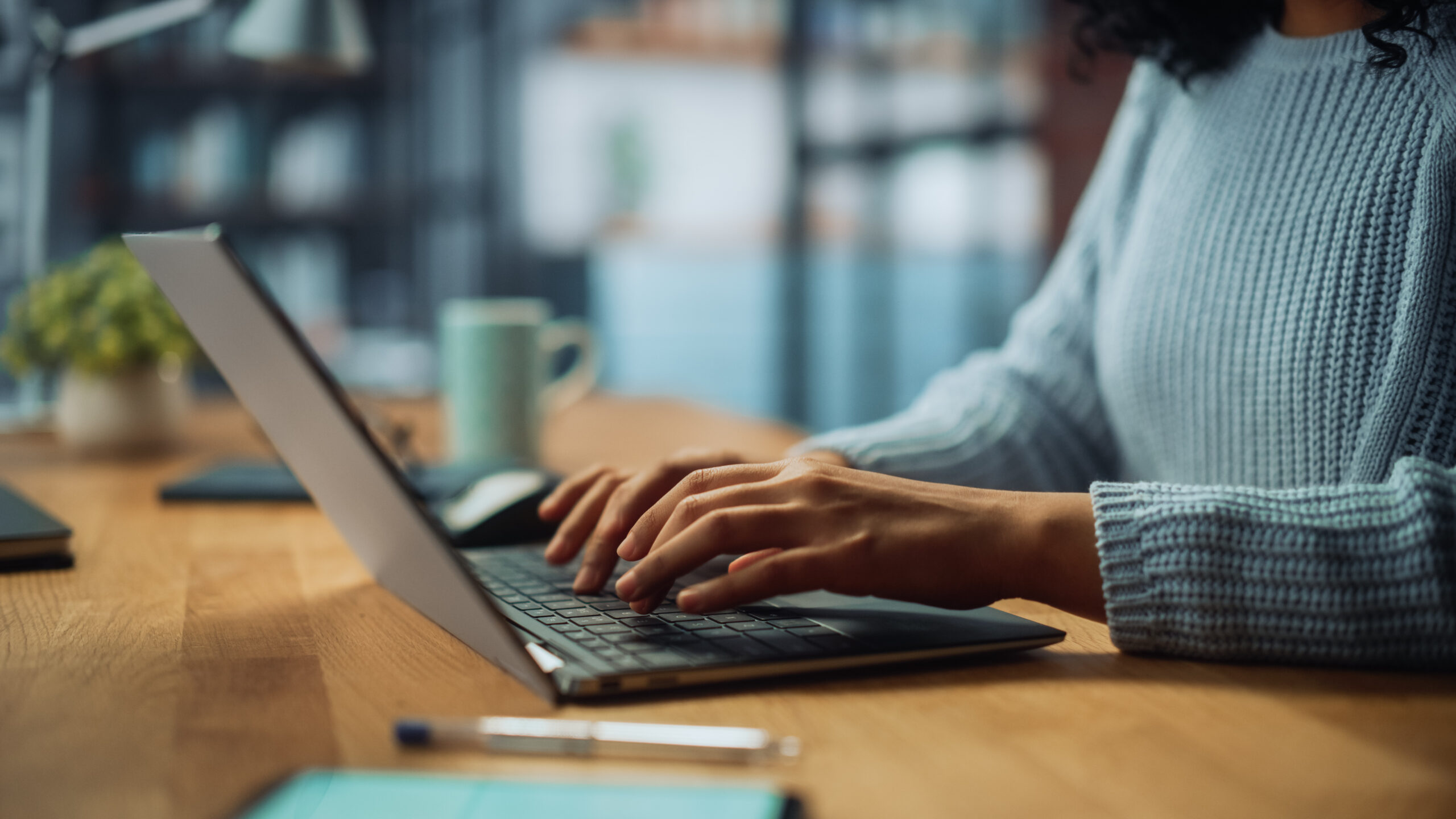 A person's hands typing on a laptop keyboard